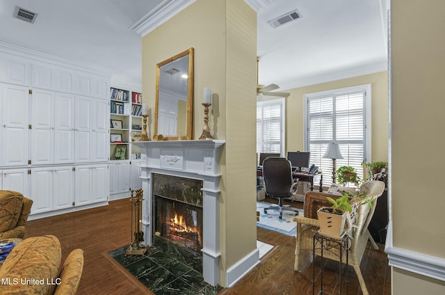 interior space featuring ceiling fan, crown molding, a fireplace, and dark wood-type flooring