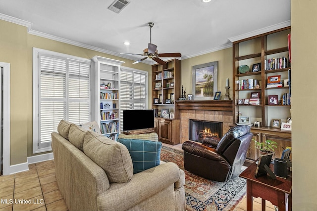 living room featuring crown molding, a fireplace, light tile patterned floors, and ceiling fan