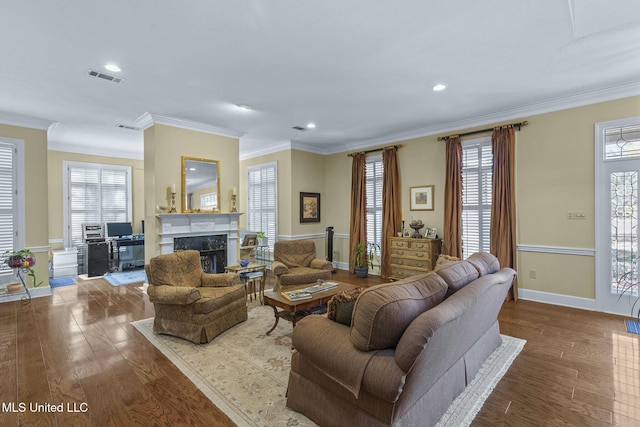 living room featuring crown molding, wood-type flooring, a fireplace, and a wealth of natural light