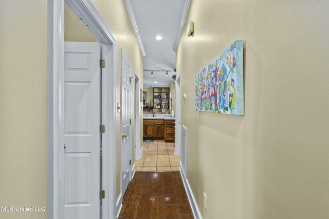 corridor with sink, light tile patterned flooring, track lighting, and ornamental molding