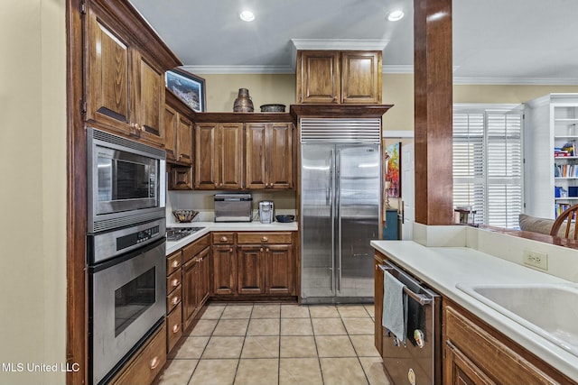 kitchen featuring built in appliances, crown molding, sink, and light tile patterned floors