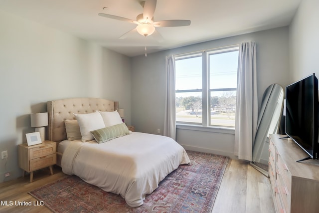 bedroom with baseboards, a ceiling fan, and light wood-style floors