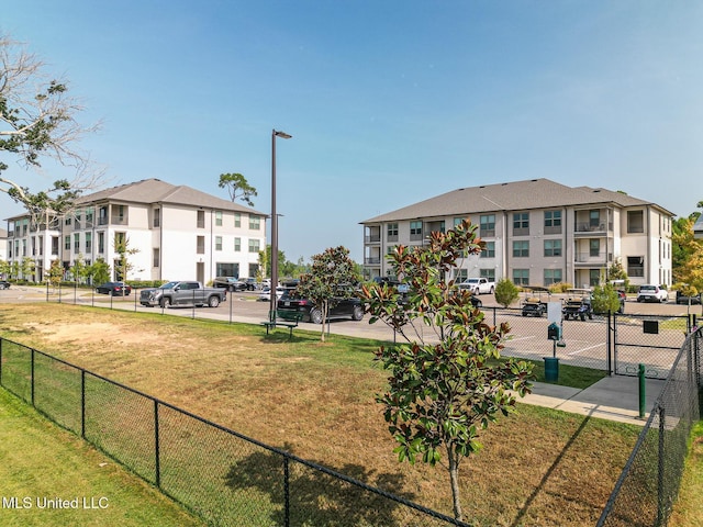 surrounding community with a residential view, fence, and a lawn