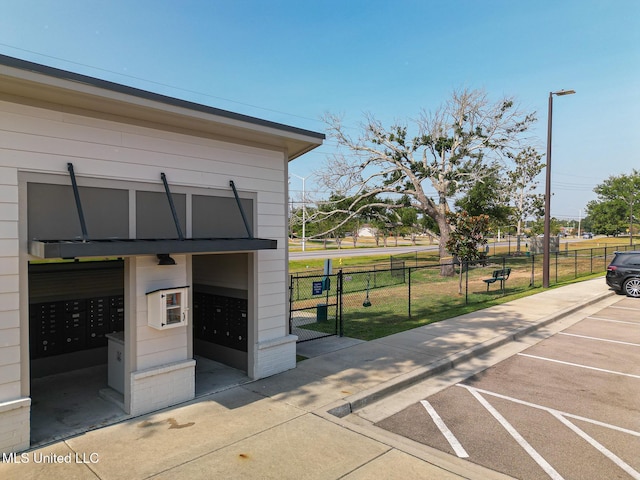 surrounding community featuring uncovered parking, a lawn, mail area, a gate, and fence