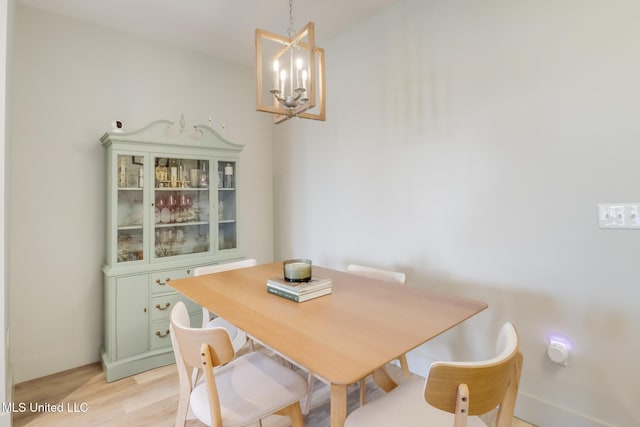 dining space featuring light wood-style flooring, a chandelier, and baseboards