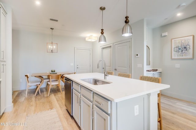 kitchen featuring light wood finished floors, visible vents, a sink, light countertops, and stainless steel dishwasher