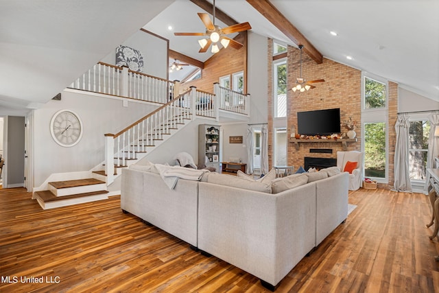 living room featuring a healthy amount of sunlight, high vaulted ceiling, wood-type flooring, and a brick fireplace