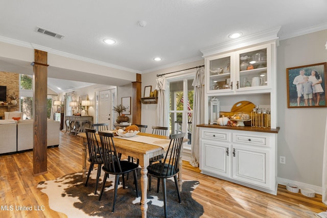 dining space with crown molding and light hardwood / wood-style flooring