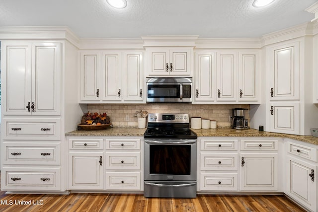 kitchen with appliances with stainless steel finishes, wood-type flooring, and backsplash