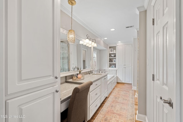 bathroom featuring built in features, hardwood / wood-style floors, vanity, a notable chandelier, and ornamental molding