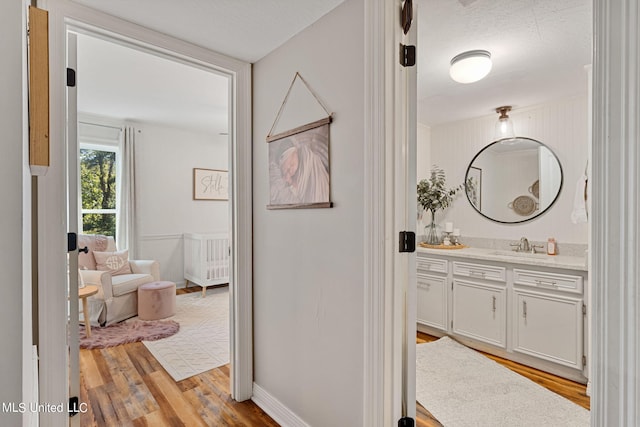 corridor featuring light hardwood / wood-style floors, a textured ceiling, and sink