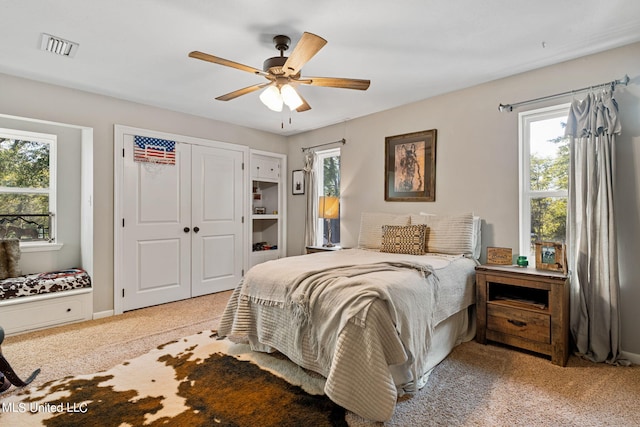 carpeted bedroom with multiple windows, a closet, and ceiling fan