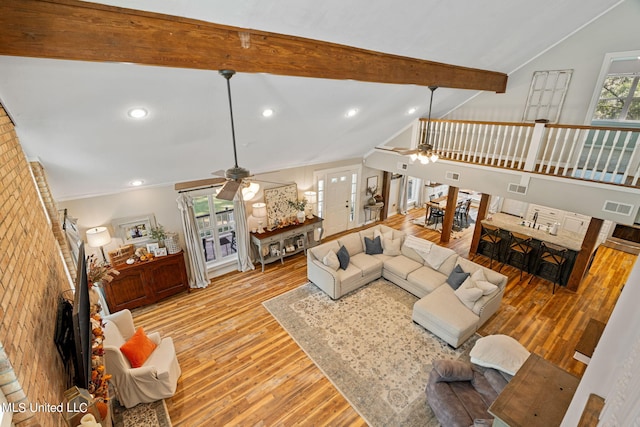 living room with beam ceiling, light hardwood / wood-style flooring, high vaulted ceiling, and ceiling fan