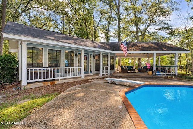 view of swimming pool featuring a patio area, a diving board, and an outdoor hangout area