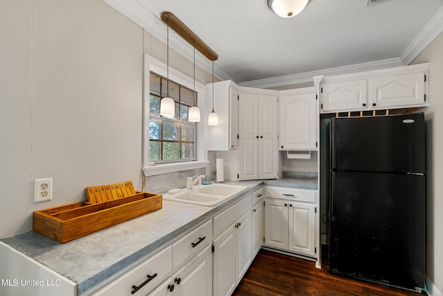 kitchen with black fridge, dark wood-type flooring, sink, decorative light fixtures, and white cabinets