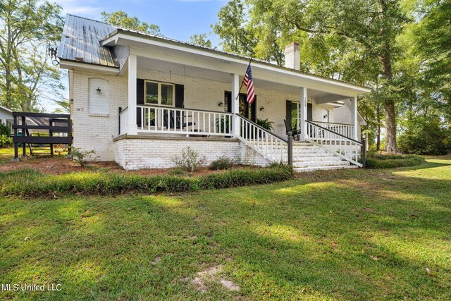 ranch-style home featuring covered porch and a front yard