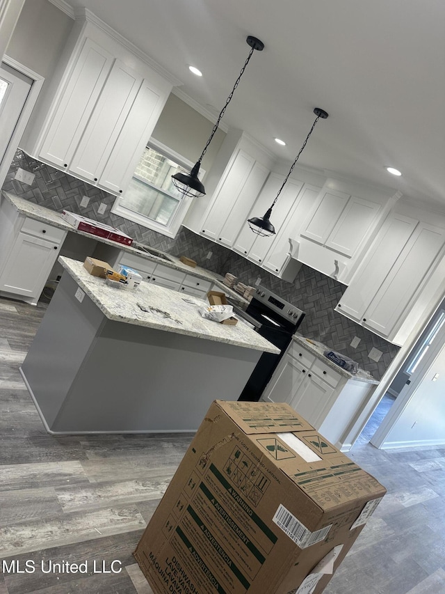 kitchen with a center island, light stone countertops, hanging light fixtures, white cabinets, and dark hardwood / wood-style floors