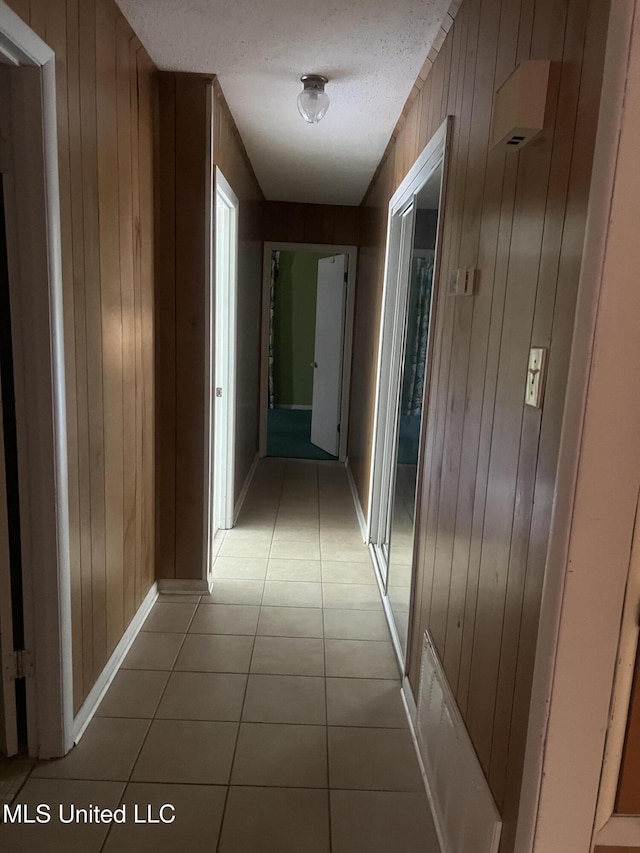 241 Iroquois St, Biloxi, MS 39530 - corridor featuring wooden walls, light tile patterned floors, baseboards, and a textured ceiling