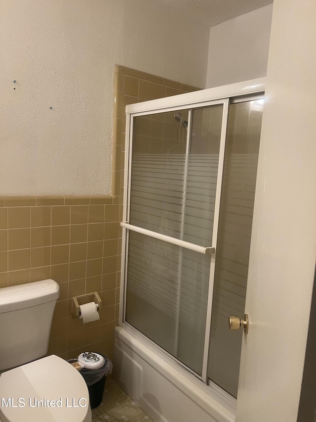 241 Iroquois St, Biloxi, MS 39530 - bathroom with enclosed tub / shower combo, toilet, tile walls, and wainscoting