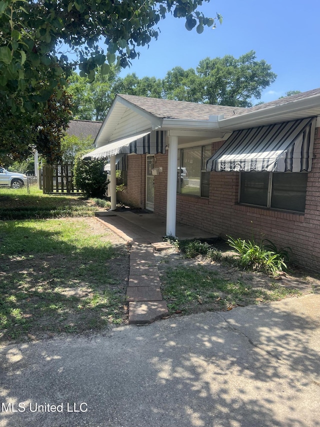 241 Iroquois St, Biloxi, MS 39530 - view of property exterior featuring brick siding, roof with shingles, and a carport