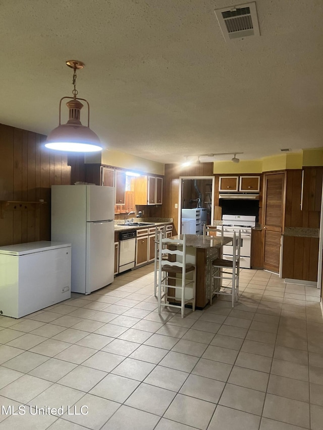 241 Iroquois St, Biloxi, MS 39530 - kitchen with white appliances, a breakfast bar, under cabinet range hood, light tile patterned floors, and a textured ceiling