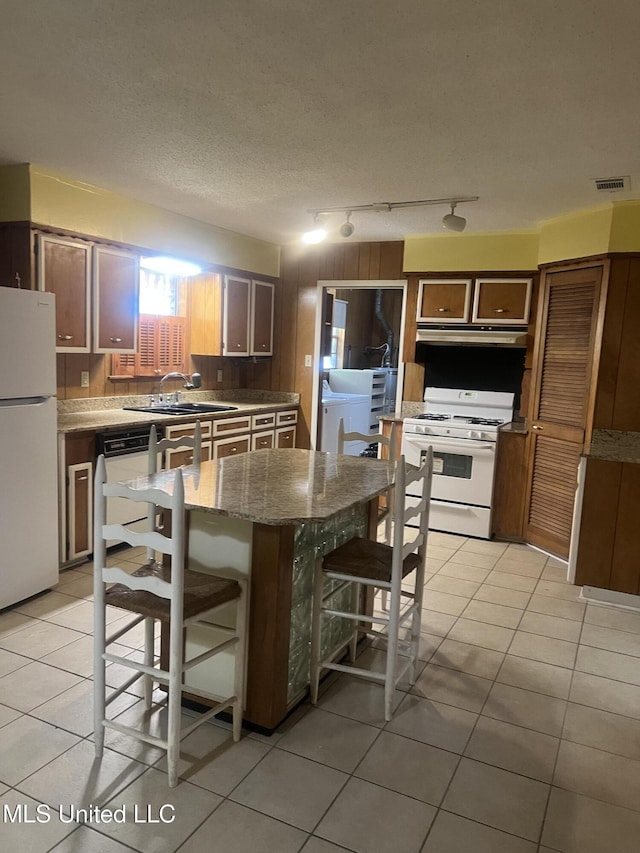 241 Iroquois St, Biloxi, MS 39530 - kitchen with white appliances, a sink, a kitchen bar, and light tile patterned flooring