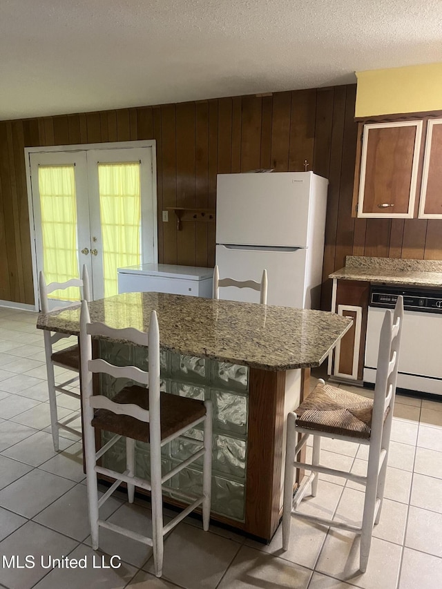 241 Iroquois St, Biloxi, MS 39530 - kitchen featuring white appliances, wooden walls, light tile patterned floors, a textured ceiling, and french doors