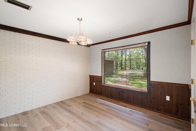 406 Springwood Cir, Terry, MS 39170 - empty room featuring a wainscoted wall, brick wall, a chandelier, wood finished floors, and ornamental molding
