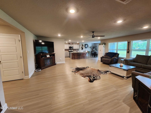 154 Magnolia Farms Dr, Lucedale, MS 39452 - living room with a textured ceiling, a ceiling fan, recessed lighting, a fireplace, and light wood-style floors