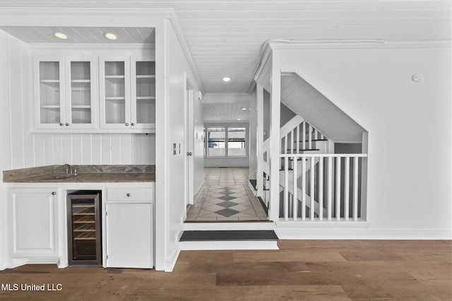 bar featuring ornamental molding, dark hardwood / wood-style flooring, beverage cooler, and white cabinetry