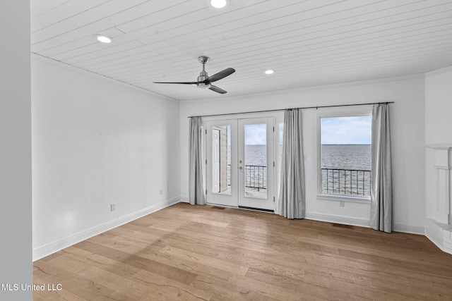 spare room featuring french doors, light wood-type flooring, ceiling fan, wooden ceiling, and a water view