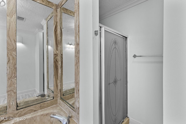 bathroom featuring a textured ceiling, crown molding, and walk in shower