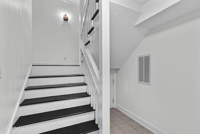 stairway featuring a textured ceiling and tile patterned flooring