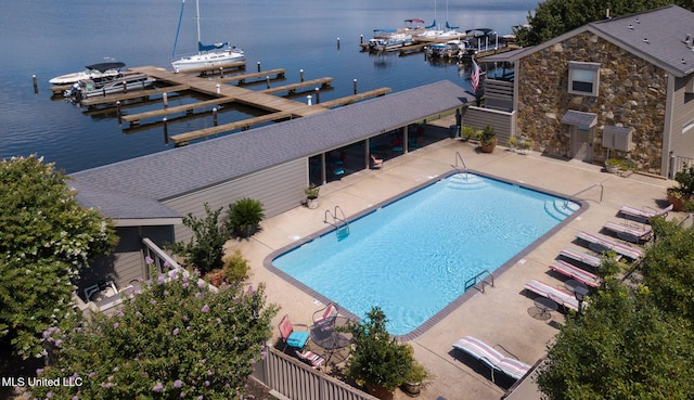 view of pool with a dock, a water view, and a patio area