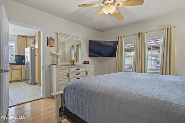 bedroom with ceiling fan, stainless steel fridge, and light wood-type flooring