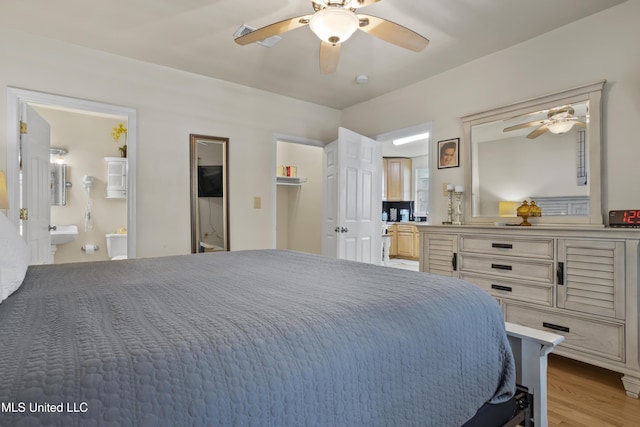 bedroom with ceiling fan, light wood-type flooring, and ensuite bath