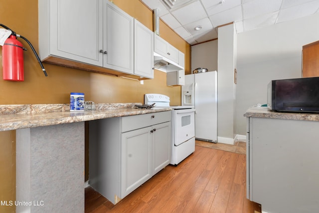 kitchen featuring white cabinetry, light stone counters, light hardwood / wood-style floors, a drop ceiling, and white appliances