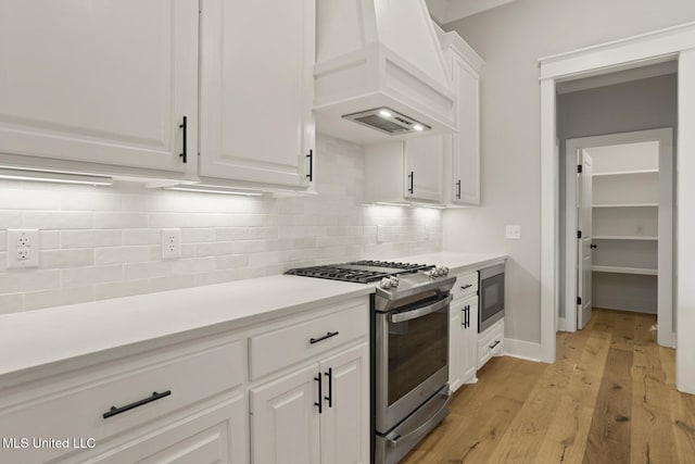 302 Wind Cv, Madison, MS 39110 - kitchen with appliances with stainless steel finishes, premium range hood, light wood-style floors, and decorative backsplash