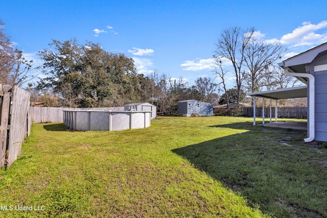 view of yard with a fenced backyard, a storage unit, a fenced in pool, and an outbuilding