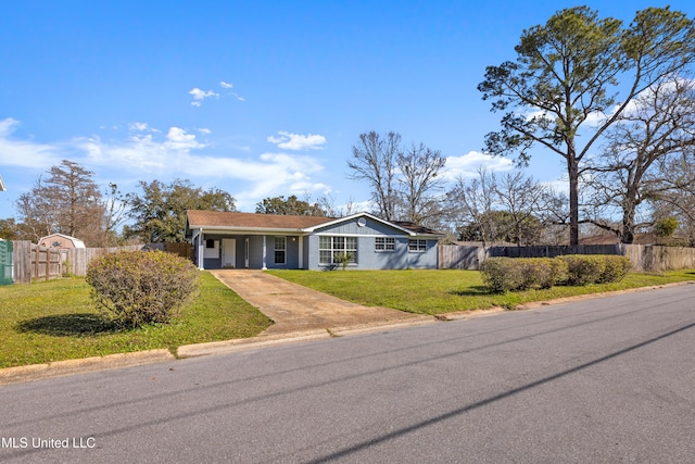 view of front facade featuring driveway, fence, and a front lawn