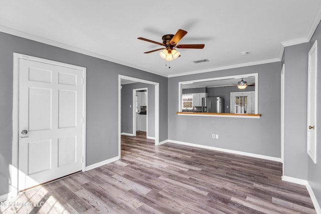 unfurnished living room with crown molding, visible vents, a ceiling fan, wood finished floors, and baseboards