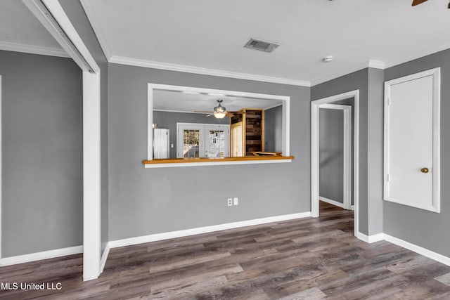 spare room featuring baseboards, visible vents, wood finished floors, and ornamental molding