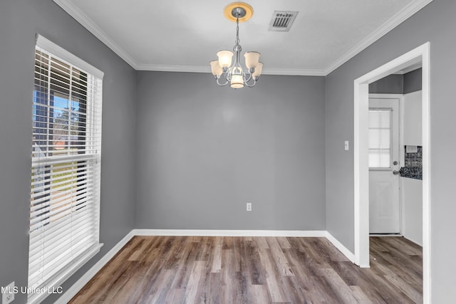 unfurnished dining area featuring an inviting chandelier, visible vents, wood finished floors, and ornamental molding