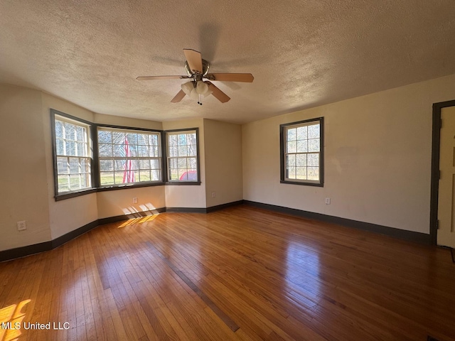 unfurnished room featuring a wealth of natural light, wood-type flooring, and baseboards