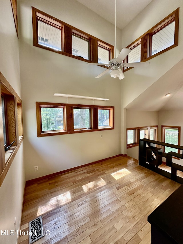 211 Monterey Dr, Clinton, MS 39056 - unfurnished living room featuring a towering ceiling, ceiling fan, light wood-style floors, plenty of natural light, and baseboards