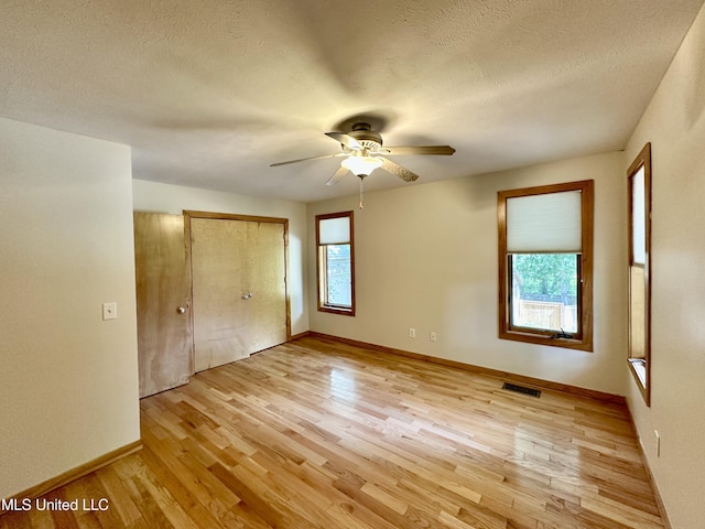 211 Monterey Dr, Clinton, MS 39056 - unfurnished bedroom with light wood finished floors, baseboards, a textured ceiling, a closet, and a ceiling fan