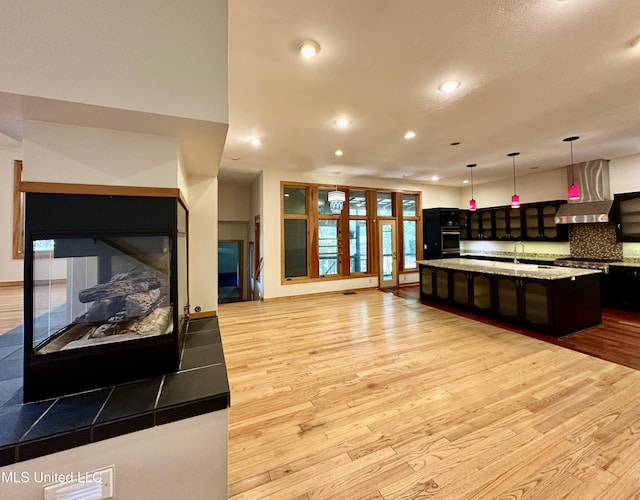 211 Monterey Dr, Clinton, MS 39056 - kitchen featuring wall chimney exhaust hood, light wood-style flooring, open floor plan, recessed lighting, and a large island