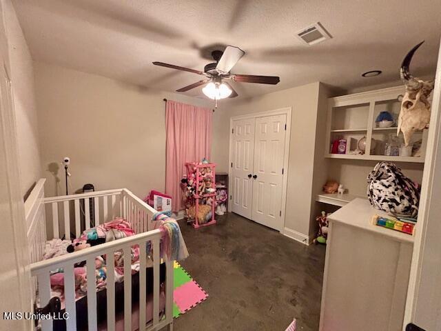 bedroom with a crib, a closet, and ceiling fan