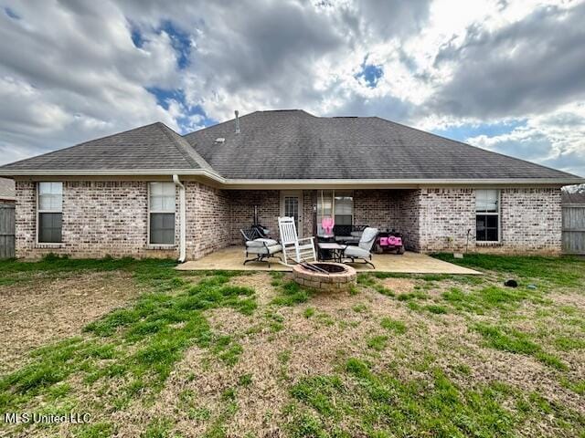 rear view of property with a fire pit, a lawn, and a patio