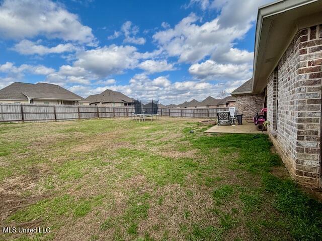 view of yard with a trampoline and a patio area